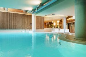 a large swimming pool in a hotel with white chairs at Hotel Meersinn - Binz in Binz