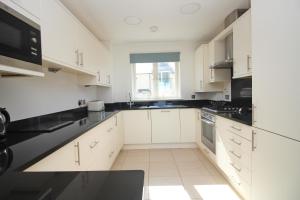 eine Küche mit weißen Schränken und schwarzen Arbeitsplatten in der Unterkunft BY THE BEACH, The Quies, Beach House in Saint Merryn