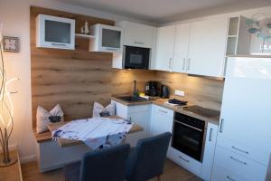 a kitchen with white cabinets and a table with chairs at Deichnähe C in Norddeich