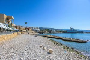 a beach with rocks and the water and buildings at Beit Chams 3 Suites in Batroun in Batroûn