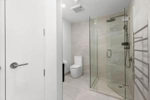 a bathroom with a glass shower and a toilet at Mountainview Escape | Stylish, BBQ, and Parking in Wanaka +18 photos
