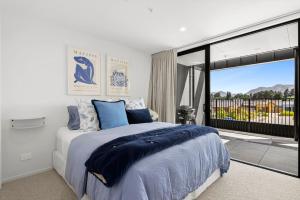 a bedroom with a large bed and a large window at Mountainview Escape | Stylish, BBQ, and Parking in Wanaka