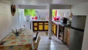a kitchen with a table and a refrigerator at Résidence Pom'Kanel in Sainte-Rose