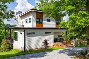 a white house with a porch and a deck at Level Up 3br Fall Retreat, Hot Tub, Firepit Dogs in Young Harris