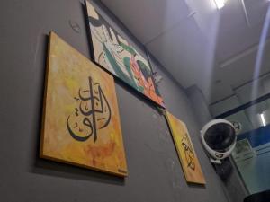 Una pared con dos cuadros con una cámara. en PIA road, en Lahore