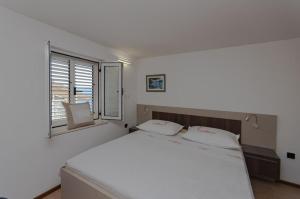 Un dormitorio con una gran cama blanca y una ventana. en Villa Roko, en Omiš