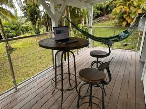 eine Veranda mit einer Hängematte und einem Laptop auf einem Tisch in der Unterkunft Studio confortable à Petit-Bourg avec terrasse 30 m² in Petit-Bourg