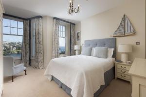 a bedroom with a bed and a chair and windows at Dolly's Plaice, Fowey in Fowey