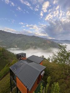 a house with a roof on a hill with fog in the valley at Northland Bungalows in Çayırdüzü