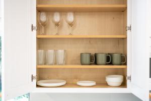 a cupboard with dishes and wine glasses in it at Private Tropical Beach Oasis - Aloe in Cape Canaveral +42 photos