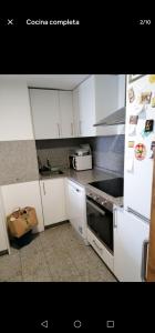 Una cocina con gabinetes blancos y un horno de estufa. en Estudio con piscina comunitaria, en Vigo