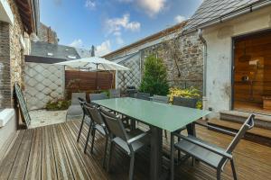 a table with chairs and an umbrella on a deck at Le Cosy de Claire in La Bourboule
