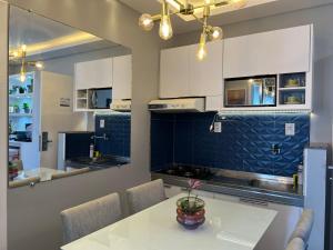 a kitchen with white cabinets and a table with a vase on it at Saint Martin Flat Fortaleza in Fortaleza