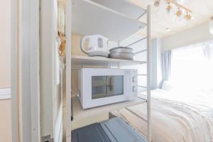 a small room with a microwave and a bed at The Nest Koenji Cozy Stay near Station Easy Access to Shinjuku in Tokyo