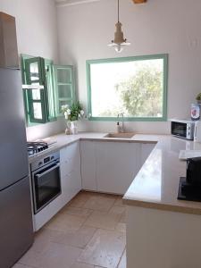a kitchen with white cabinets and a large window at Villa Aquilo in Megali Ammos