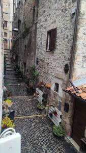un vicolo con un edificio in pietra con scale e fiori di Secret Room Anagni ad Anagni