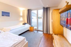 a hotel room with a bed and a flat screen tv at Oldenburg 03 in Wangerooge
