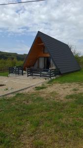 a building with a black roof with benches around it at Casuta de la ferma in Băiculeşti