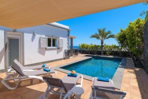 patio z basenem i krzesłami oraz willa w obiekcie Villa Loretta w Puerto del Carmen