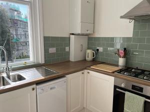 a kitchen with white cabinets and green tiles at Period Suntrap Gem, Sea View 5 min to Sea and Station in Hollington