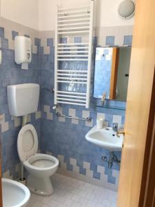 La salle de bains est pourvue de carrelage bleu, de toilettes et d'un lavabo. dans l'établissement Villa Grazia, à Rimini