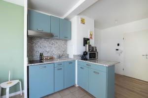 a kitchen with blue cabinets and a microwave at Studio 30 m2 tout confort - RER à 3 min, accès Paris & Disneyland in Villiers-sur-Marne +1 photo
