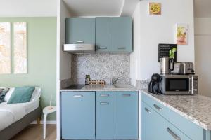 a kitchen with blue cabinets and a microwave at Studio 30 m2 tout confort - RER à 3 min, accès Paris & Disneyland in Villiers-sur-Marne