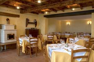 a restaurant with white tables and chairs and a fireplace at Malga Mariech in Valdobbiadene