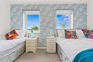 two beds in a room with two windows at Black Friday Deal - Stunning 2BR House with Garden, Netflix Walk 30min to Alton Tower in Stoke on Trent