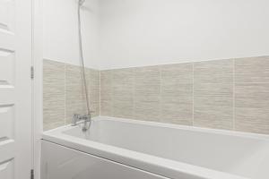 a white bath tub in a bathroom with tiles at Black Friday Deal - Stunning 2BR House with Garden, Netflix Walk 30min to Alton Tower in Stoke on Trent +34 photos