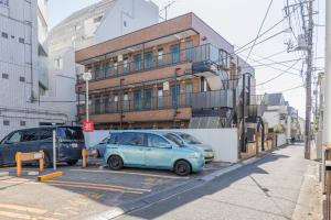 two cars parked in a parking lot in front of a building at The Nest Koenji Cozy Stay near Station Easy Access to Shinjuku in Tokyo