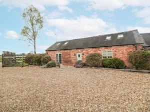 a red brick house with a gravel driveway at Barnfields Holiday Cottage in Kingsley
