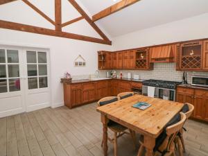 a kitchen with wooden cabinets and a wooden table at Barnfields Holiday Cottage in Kingsley