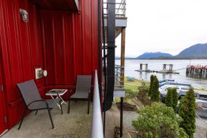 a red building with chairs and a table with a view of the water at Tofino Waterfront Condo in Tofino