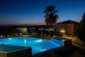 a swimming pool at night with a palm tree at Kefalonian Mill - Oneira Villas in Trapezaki