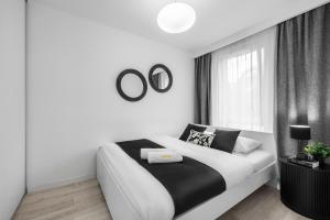 a white bedroom with a black and white bed and a window at Emihouse CityVibe Apartments in Rzeszów