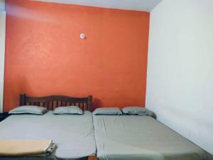 two beds in a room with an orange wall at Ishwar Place Rooms and Cafe Gokarna in Gokarna
