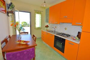 une cuisine avec des armoires orange et une table avec une assiette dessus dans l'établissement Appart Ginestra SIX Li Pali by Salento Prime, à Torre Pali
