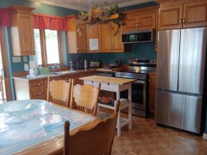 a kitchen with a table and a stainless steel refrigerator at 3 Bedrooms 3 beds near metro -2 Parking Free in Montréal