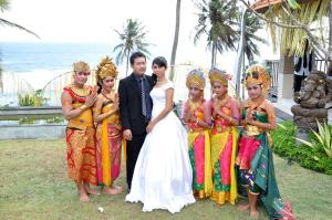 a bride and groom posing with a group of girls at Villa Rumah Pantai Bali in Selemadeg