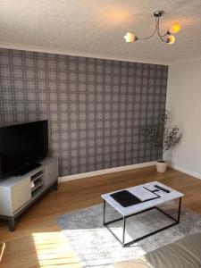 a living room with a tv and a coffee table at Kelpies Serviced Apartments- McLaughlan in Falkirk +5 photos
