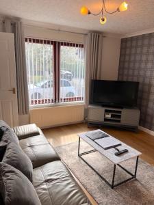 a living room with a couch and a flat screen tv at Kelpies Serviced Apartments- McLaughlan in Falkirk