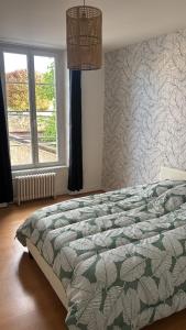 a bedroom with a bed and a window and a chandelier at Appartement cosy centre-ville in Falaise