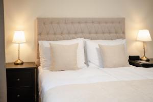 a bedroom with a white bed with pillows and two lamps at Monika Apartment in Bogács