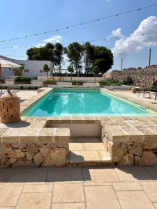 una piscina con un muro di pietra intorno di Masseria Voluzzi a Copertino