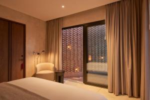 瓦哈卡市Casa Cunda的一间卧室，配有一张床和一扇带椅子的窗户