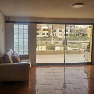 un soggiorno con divano e una grande porta scorrevole in vetro di Hostal Turístico El Cajamarquez a Lima