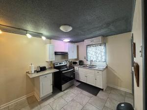 ナイアガラフォールズにあるGetaway Home at Niagara!のキッチン(白いキャビネット、黒いコンロ付)