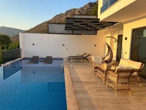 a swimming pool with chairs and a table next to a house at Kalkan da Vaıllant Villa in Kaş