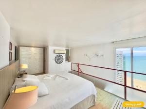 a bedroom with a bed and a balcony with the ocean at Loft Praia - Meireles in Fortaleza